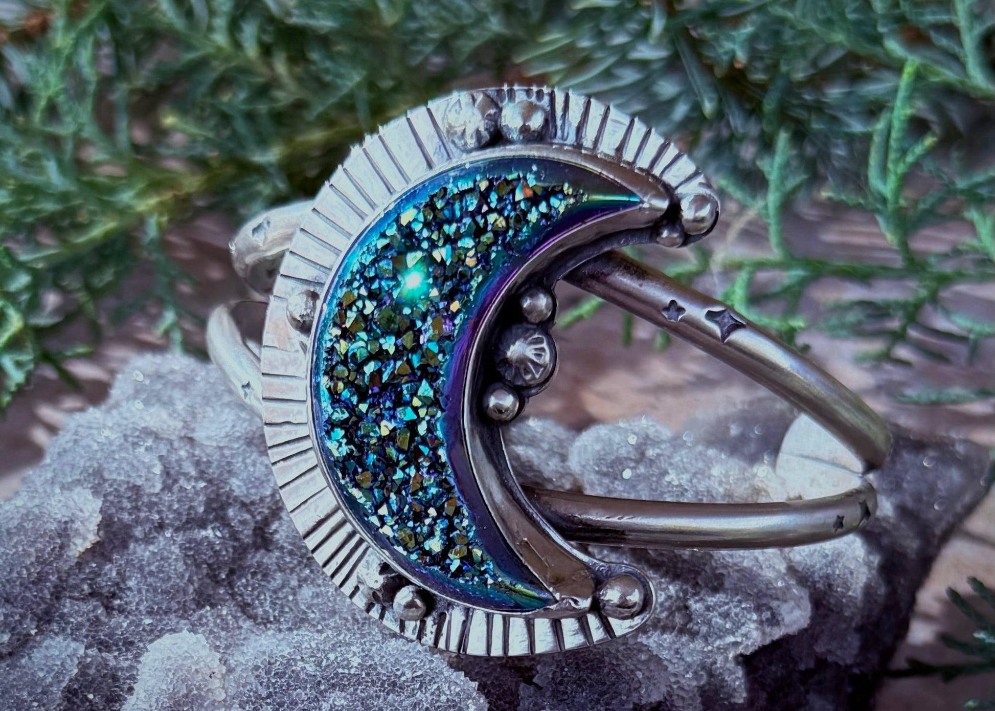 Silver ring with blue gemstone on a textured surface with greenery