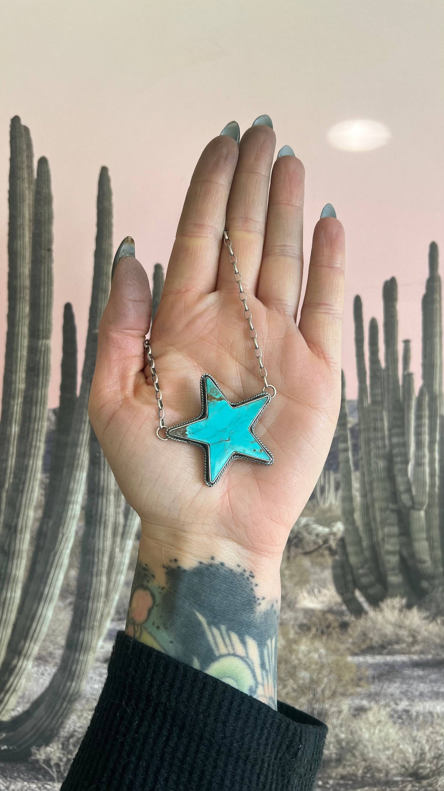 Kingman Turquoise Statement Necklace featuring a star-shaped turquoise pendant displayed against a desert cactus background.