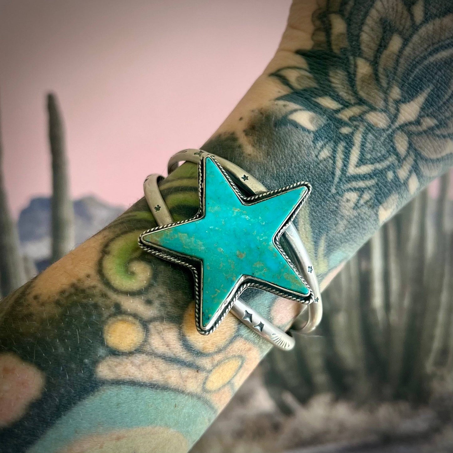 Kingman Turquoise Statement Cuff featuring a star-shaped turquoise stone set in sterling silver with hand-stamped details, worn on a tattooed wrist. Ideal for S/M wrist sizes.