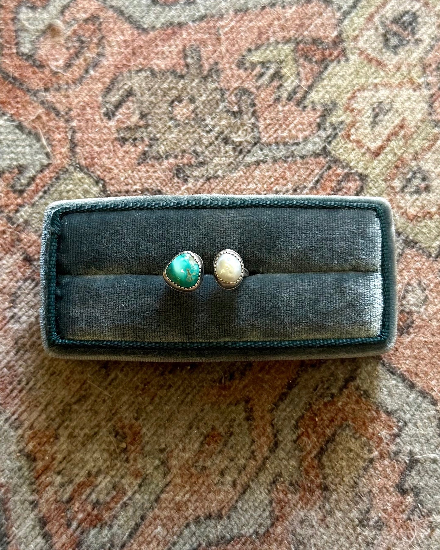 Two pearls in a black box on a patterned rug